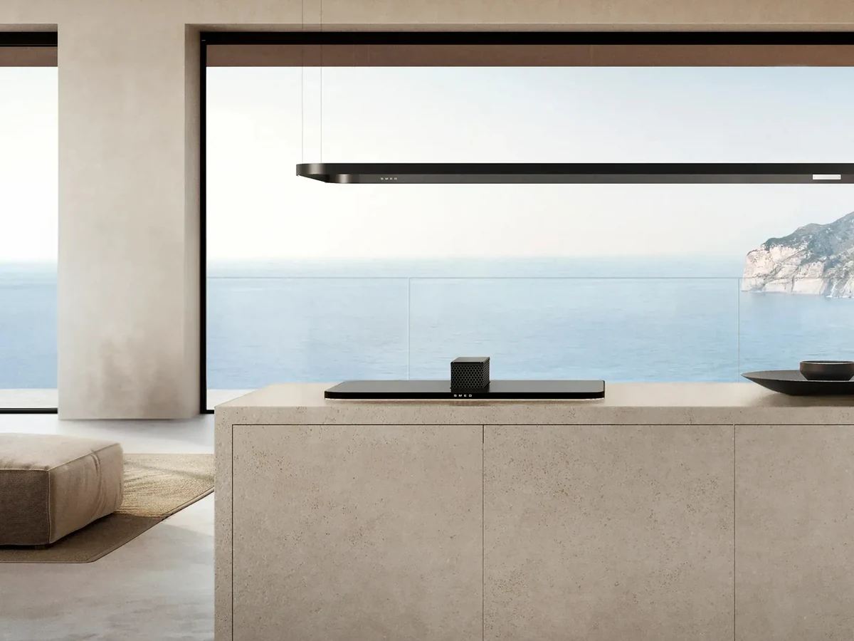 Coifa de ilha Smeg suspensa sobre bancada com vista para o mar